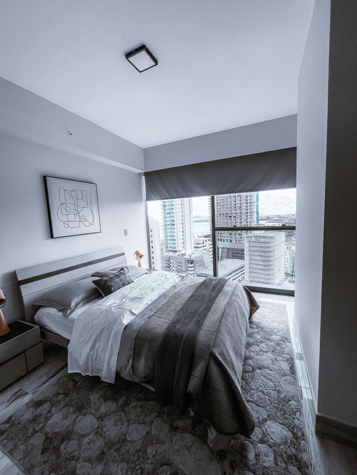 Contemporary minimalist bedroom design with cityscape window view, inviting modern aesthetic.