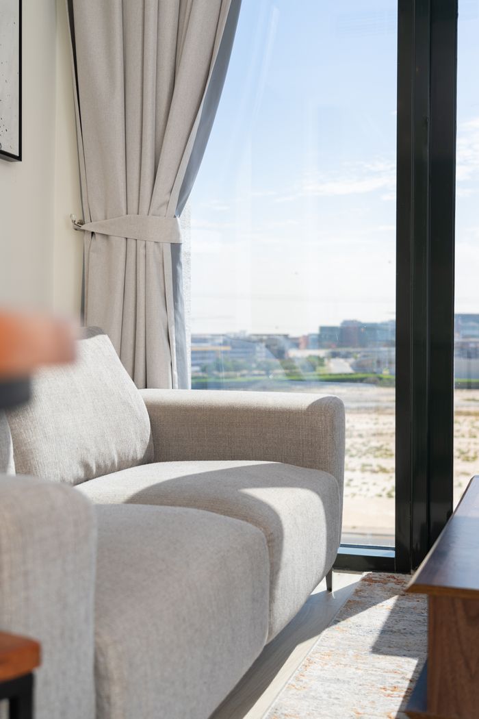 About Bright living room with a modern sofa and panoramic city view through a large window.