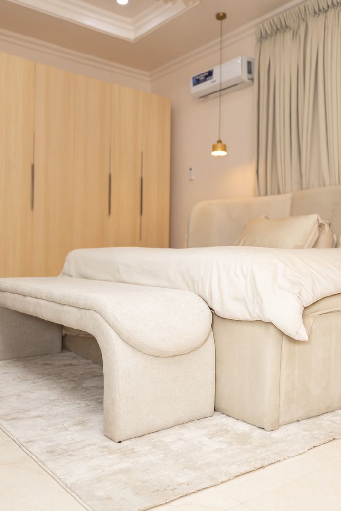 Stylish minimalist bedroom with beige decor, modern bed and soft lighting.